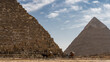 Two pyramids of Giza- Cheops and Chephren on a background of blue sky and clouds. Close-up. The ancient masonry walls are visible. At the foot there are horses harnessed to carts. Egypt