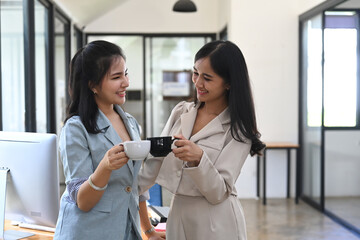 Wall Mural - Two business women discussing project or sharing news during coffee break in office.