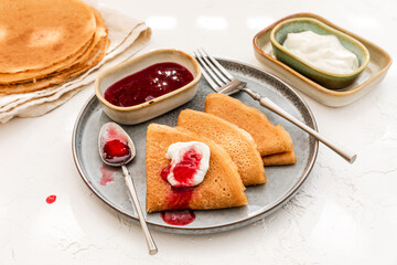 Wall Mural - Pancakes served on a plate with sour cream and berry jam