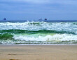 Panoramic landscape seascape coastal beach view of Table Mountain with tankers and container ships anchoring, swell waves at Blouberg Beach on misty foggy day with low hanging clouds