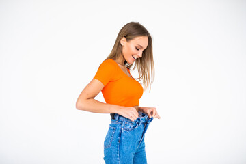 Wall Mural - Woman after losing weight in old big jeans isolated on white background.