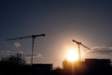 Silhouette of a two tall crane and construction site for commercial office of residential property. Construction industry. Modern technology. Investment.