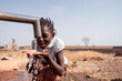 Clean water supply concept: young black African native girl drinking healthy fresh water from a village tap