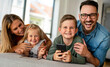 © NDABCREATIVITY - Happy young family having fun time at home. Parents with children using tablet