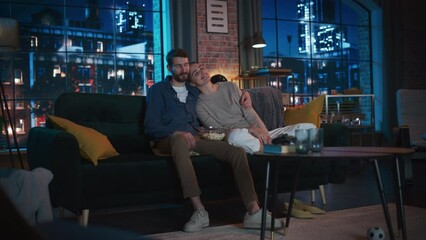 Aufkleber - Portrait of Beautiful Couple Spending Time at Home, Sitting on a Couch, Hugging and Watching Exciting TV Show in Their Stylish Loft Apartment. Man and Woman Streaming Comedy Movie and Have Good Time.