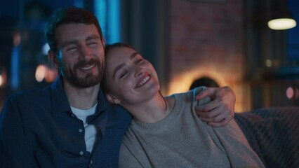 Aufkleber - Portrait of Beautiful Couple Spending Time at Home, Sitting on a Couch, Hugging and Watching Exciting TV Show in Their Stylish Loft Apartment. Man and Woman Streaming Comedy Movie and Have Good Time.