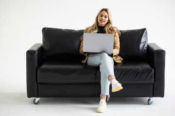 Beautiful woman on a sofa working with a laptop in white background