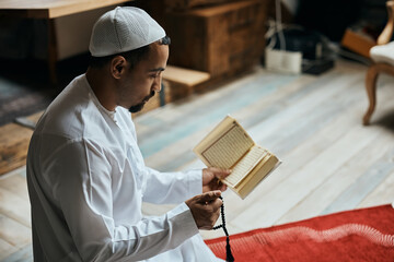 Poster - Middle Eastern man prays while reading from Koran and holding misbaha beads.