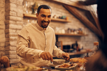 Wall Mural - Happy Middle Eastern man talks to his wife during Ramadan meal at dining table.