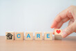 © Ratana21 - hand holding  red heart icon on wood cube , care word and house with elderly and disability person icon inside for home care for aging people, nursing house concept