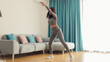 © shevtsovy - Athletic woman sports workout at home, squats. Home workout. Slim female stretching at home and weight loss workout in a living room.