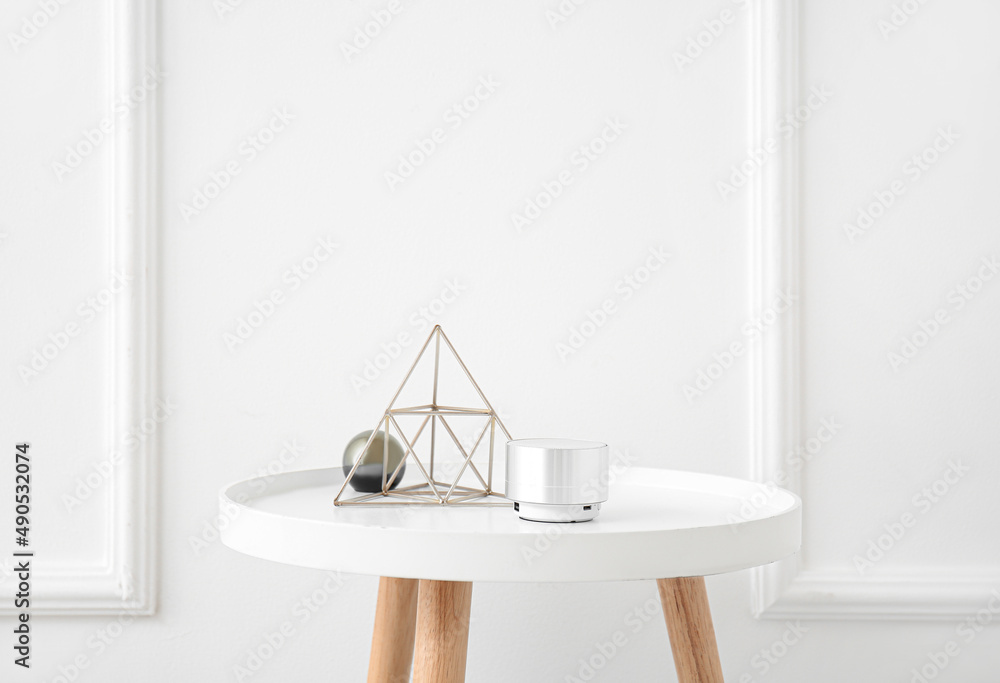 Wireless portable speaker and stylish decor on table near light wall
