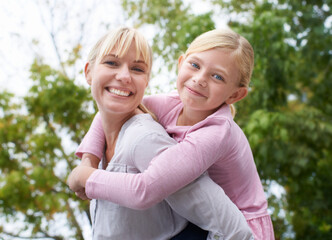 Sticker - Wrapped in my daughters love. A happy young mother givign her daughter a piggyback ride in the park.