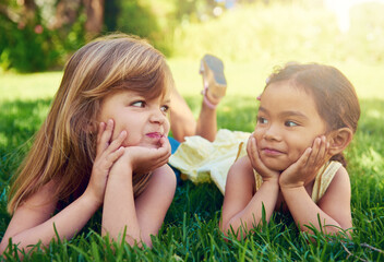 Sticker - Childhood friendship. Shot of two adorable little girls lying next to each other on the grass.