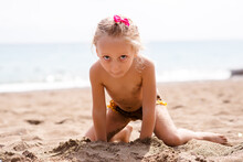 Little Adorable Girl 2-3 Years Plays Joyfully On The Beach In Sunset On Holiday