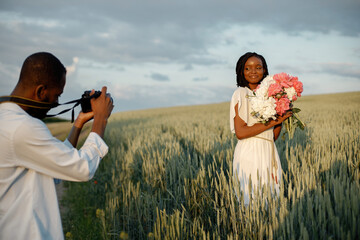 Happy couple with camera at summer field