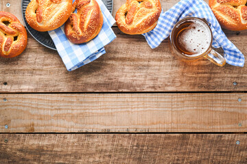 Wall Mural - Bavarian pretzels and glass of lager beer. Oktoberfest food menu, traditional salted pretzels over old  wooden background. Top view with space for text. Oktoberfest theme