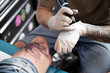 © ADDICTIVE STOCK - Anonymous tattooist making tattoo on leg of person