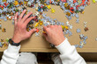 © Andres - Hand of a young boy trying to solve a puzzle, he is putting together the small pieces in various sectors. entertainment concept.