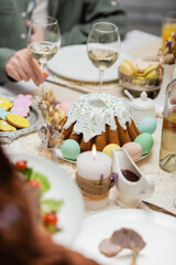 Wall Mural - partial view of man near delicious easter cake, painted eggs and wine glasses on festive table.