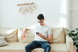 © etonastenka - A serious man sits on a sofa and watches world news or solves business problems in a business at home.