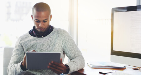 Poster - Navigating his way through the world online. Shot of a young businessman using a digital tablet in an office.