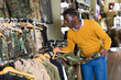 © JackF - African-american man selecting outwear in military goods store.