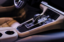 Modern Luxury Car Inside Interior With Gear Shift, Automatic Transmission, Buttons, Cup Holders And Armrest And Beige Leather Seat Detail. Close Up.