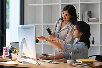 Wall Mural - Two female business colleagues discussing business project, brainstorm sharing ideas together.