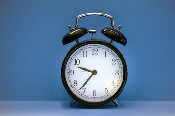 Close up of black old alarm clock on blue background