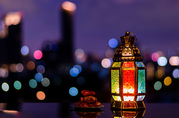 Wall Mural - Lantern and small plate of dates fruit with night sky and city bokeh light background for the Muslim feast of the holy month of Ramadan Kareem.