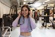 © Jelena Stanojkovic - Shot of a sporty young woman listening to music while exercising in a gym. Portrait of a happy woman using earphones at the gym