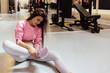 Close up of young female athlete holding her ankle in pain on sports training in a gym. Young female athlete holding her ankle in pain at gym.