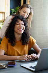 Wall Mural - Happy multiethnic teenagers holding technology gadgets using digital devices studying together.