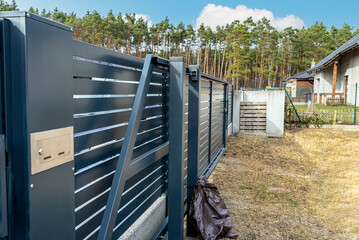 Wall Mural - Modern anthracite panel fence, visible sliding gate to the garage, view from the garden.