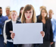 © Lucinda D B/peopleimages.com - We have a message. Portrait of a businesswoman holding a blank board with colleagues standing behind her.