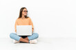 © luismolinero - Young woman with a laptop sitting on the floor in lateral position