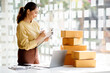 © David - Startup SME small business entrepreneur SME of freelance Asian woman using a laptop with box Cheerful success Asian woman her hand lifts up online marketing packaging box and delivery SME idea concept