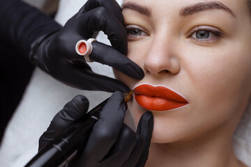 Wall Mural - Cosmetologist makes permanent makeup on a woman's face. Specialist applies a tattoo on the patient's lips close-up