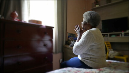 Wall Mural - A spiritual older black woman praying to God sitting in bedroom