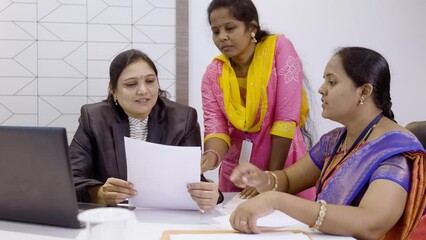 Wall Mural - Handheld shot of group of woman employees discussing about project during meeting at office - concept of teamwork, cooperation support and planning business development.