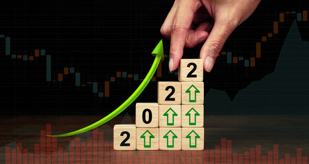 2022 Business development to success and growing growth concept. A businessman organizes a wooden block into a growing graph.                          