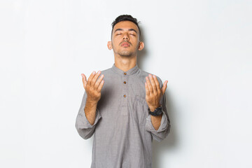 Young handsome man praying isolated on white background
