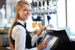I am a whiz on this till. Beautiful barmaid standing by a till smiling as she rings through a round of drinks.