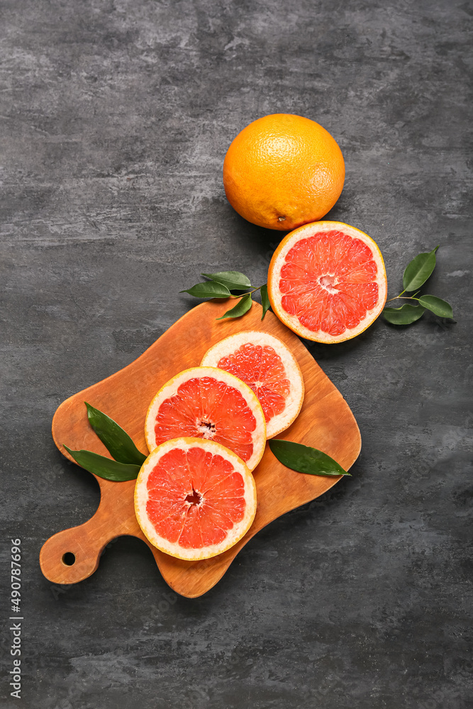 Board with fresh grapefruit slices on dark background