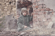 Child And  War. Poor, Homeless Child In The Ruins Of A Destroyed House. 