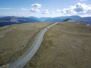 Wall Mural - Narrow traffic road passing through the empty fields against a cloudy sky on a sunny day