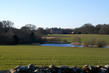 Poster - Beautiful view of calm lake surrounded by grass with an old house in the background