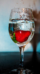 Sticker - Vertical shot of a transparent wine glass filled with water and a strawberry