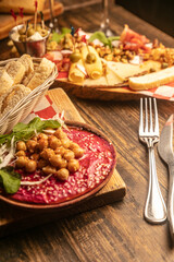 Wall Mural - Top view of baked chickpeas in a sauce and a cheese set  with olives on a wooden board